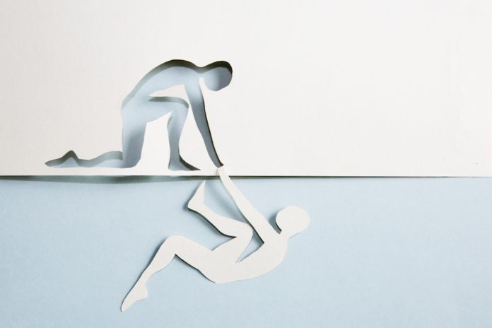 Help A man cut out of paper being helped by the cut out of a man made of paper
