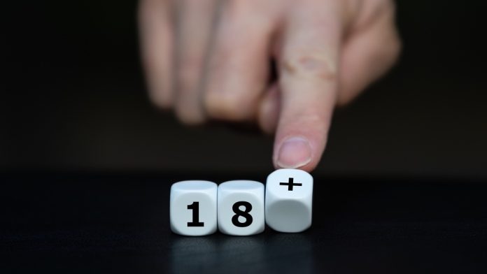 Fingers pushing dice showing 18+