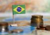 Brazil Government approves 50% tax hikes on online GGR Brazil flag next to a stack of coins