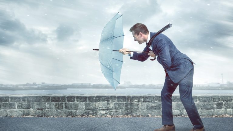 Businessman with an umbrella is facing strong headwind, like the industry is facing from legislators