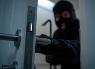 Isle of Man Government warns of criminal infiltration from Southeast Asia A thief in a balaclava sneaks behind a door
