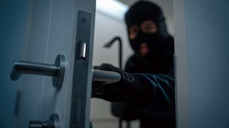 Isle of Man Government warns of criminal infiltration from Southeast Asia A thief in a balaclava sneaks behind a door