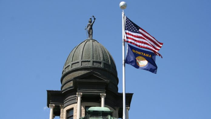 montana-sweeps-ban US and Montana state flag on a flagpole attached to a large building