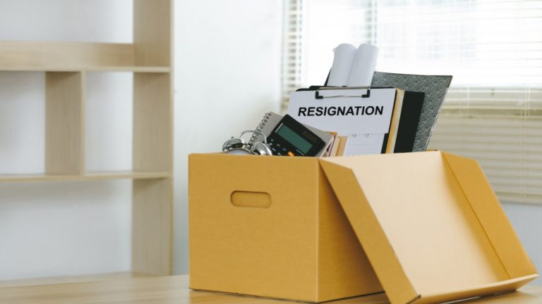 A box full of office objects and a clipboard that says the word resignation
