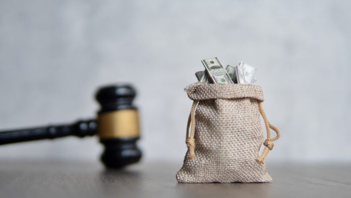 A sack of money next to a gavel, indicating that a financial penalty has been handed out