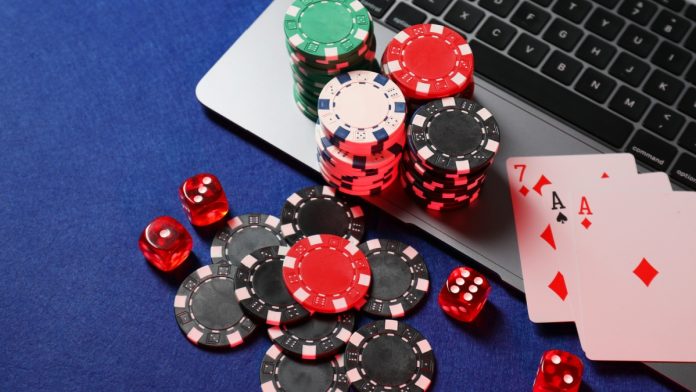 maine-online-casino-bill Poker chips and cards sit on a laptop, representing online casino