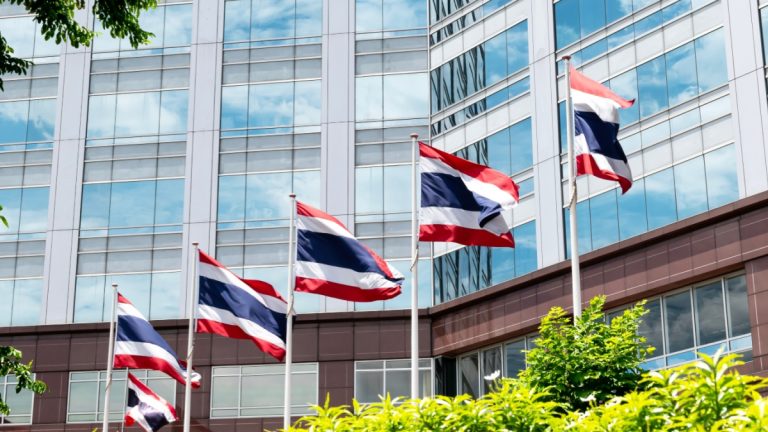 Flag poles flying the Thai flag in front of a building