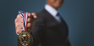 Bally’s International Interactive and Intralot seek global iGaming champion status Businessman holding gold medal