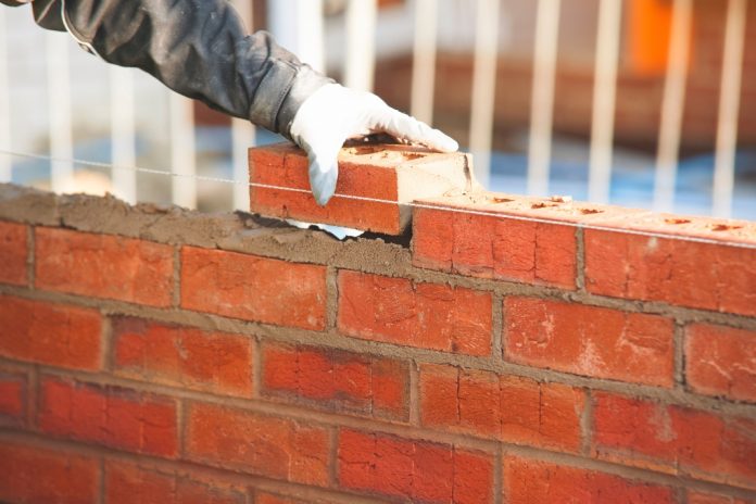 Builder building a brick wall