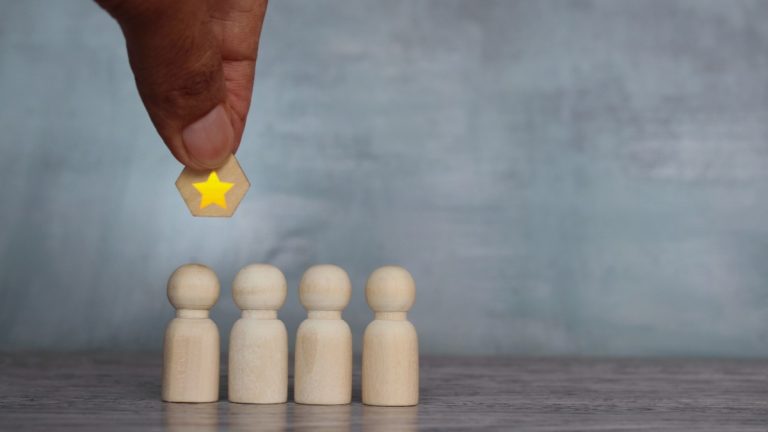 Gold star hangs over wooden figures, signifying they are about to receive recognition
