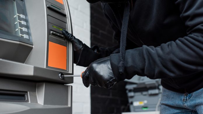 A man is pictured breaking into an ATM