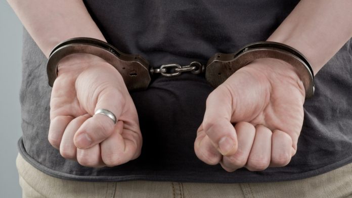 thailand-gambling-raid Man with handcuffs behind his back