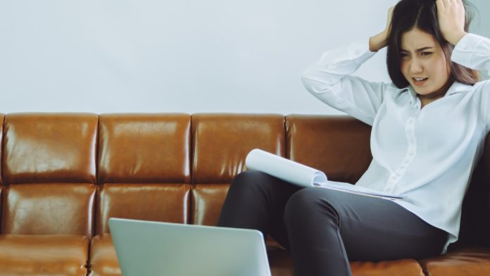 Businesswomen looks at her laptop with her hands on her head in dismay