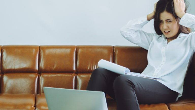 Businesswomen looks at her laptop with her hands on her head in dismay