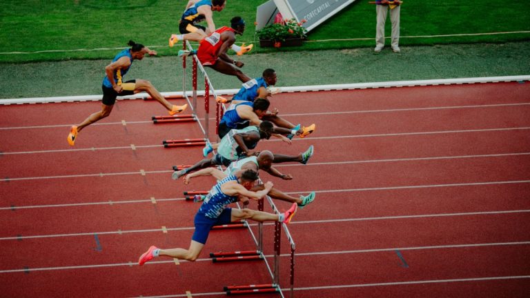 Athletes jump over hurdles