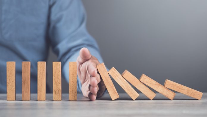 italy-gets-tough-black-market-operators Hand blocks dominoes falling