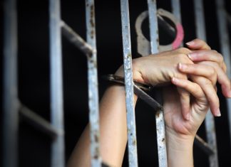 Alice Guo given life sentence for POGO-related human trafficking A womans hands cling on to the railings of a prison cell