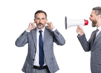 Andrew Rhodes: UK Government can’t ignore the looming crypto future Businessman shouts through megaphone at another with his fingers in his ears