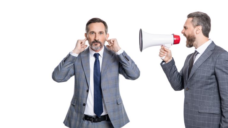 Andrew Rhodes: UK Government can’t ignore the looming crypto future Businessman shouts through megaphone at another with his fingers in his ears