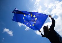 EC backs Digital Services Act as best weapon against illegal gambling Woman holds EU flag