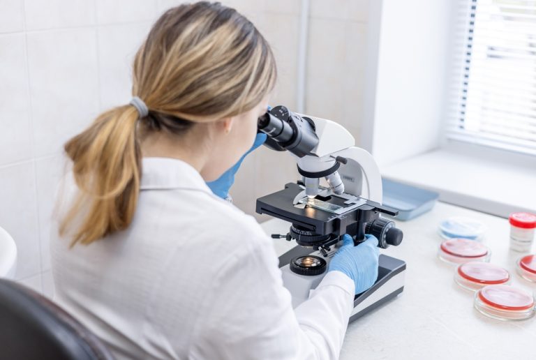 Woman looks through microscope