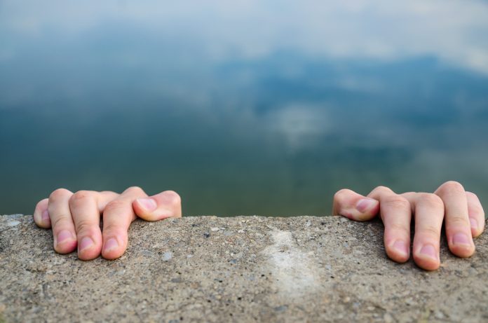 UK funding Hands holding on to a cliff edge