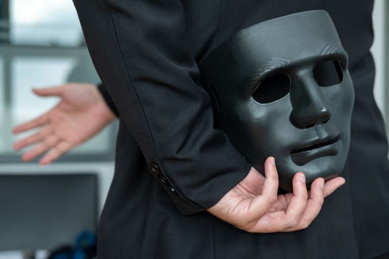 How false licensing claims continue to plague key gambling regulators Businessman holds mask behind his back