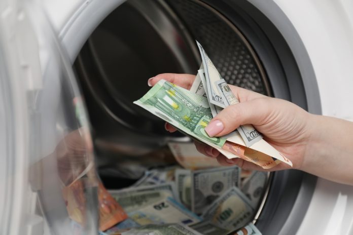 Close up of hand putting money into a washing machine