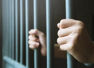 Ex-Senator’s son jailed for 132 years in Thailand amid illegal gambling crackdown Man holds on to railing of a jail cell
