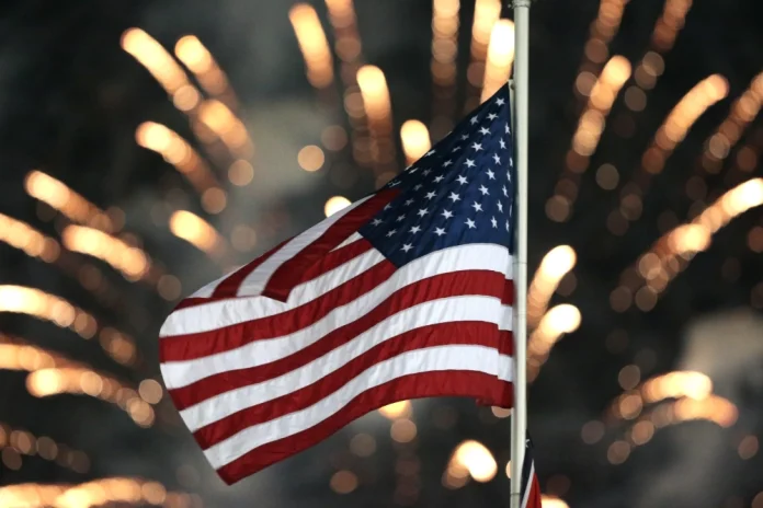 The USA flag in front of fireworks going off.